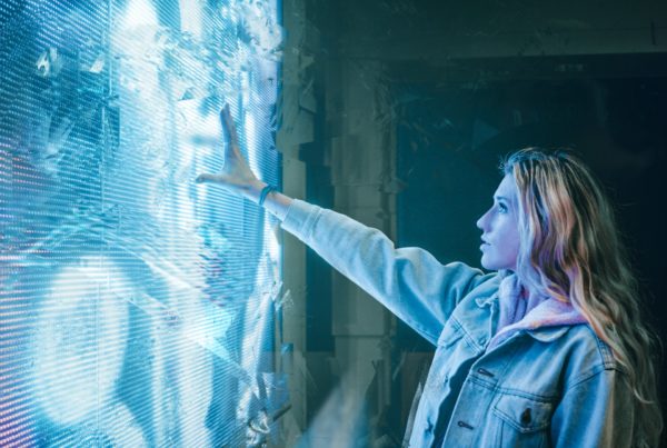 A lady reaching out into a futuristic screen.