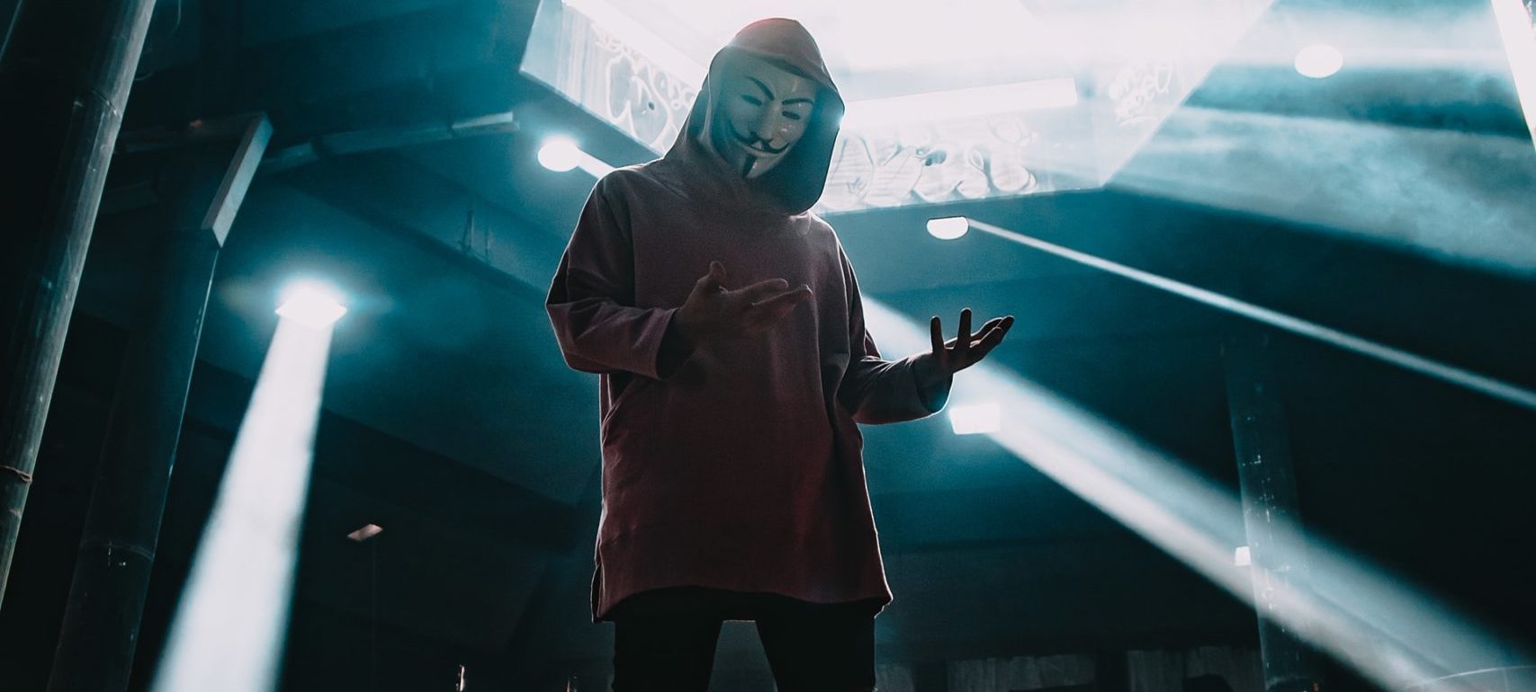 Person with mask standing under a sky light.